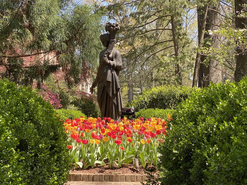 yellow and red tulips around a statue 